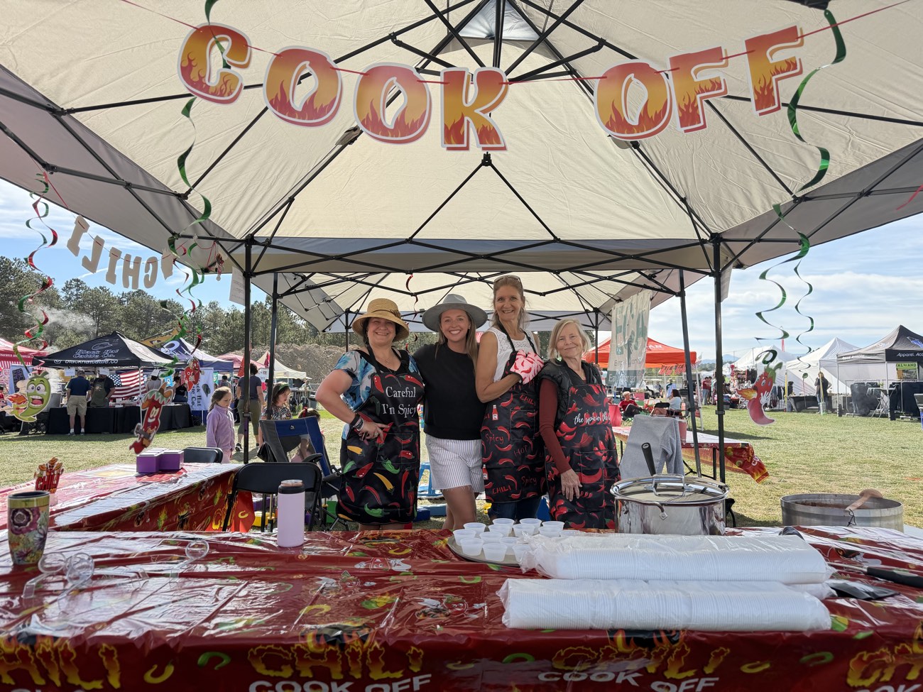 Four ECA team members in chili-pepper aprons under the Cook Off tent