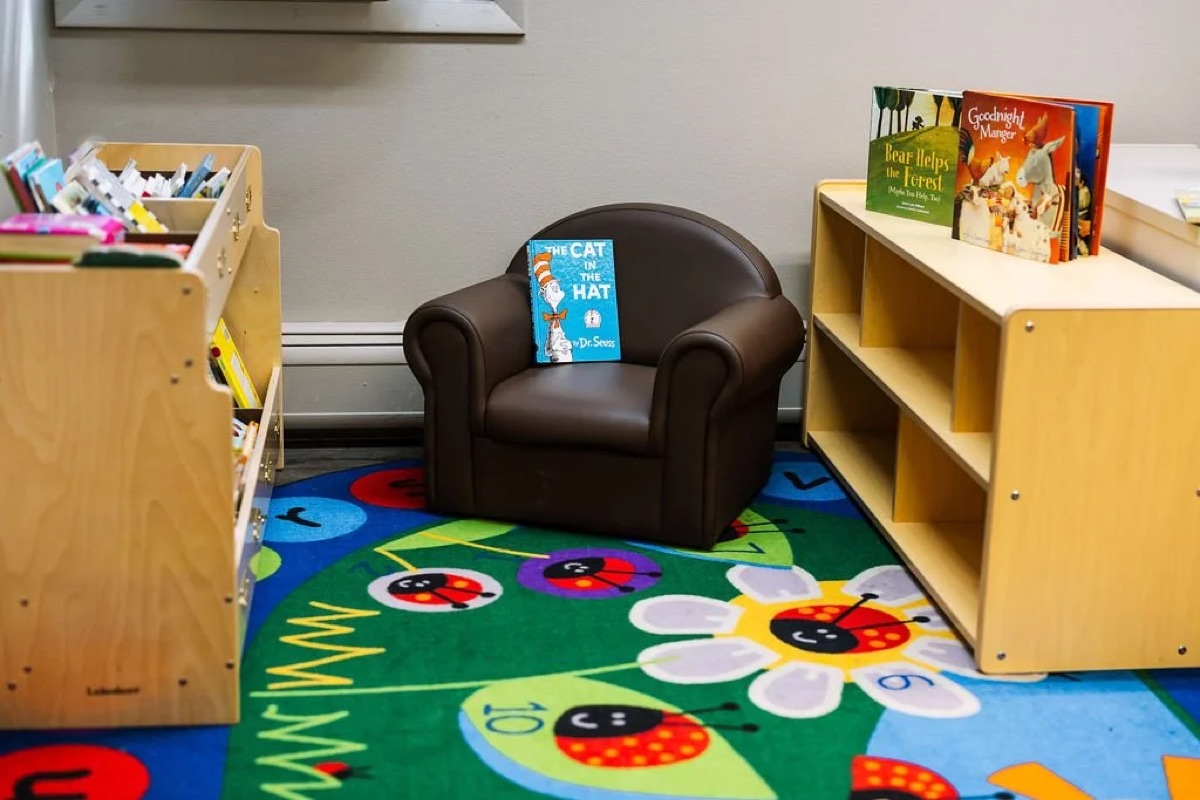 A cozy classroom reading corner with a small armchair and bookshelves